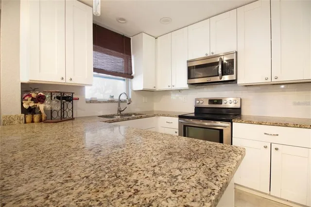 a kitchen with stainless steel appliances granite countertop a sink stove and microwave
