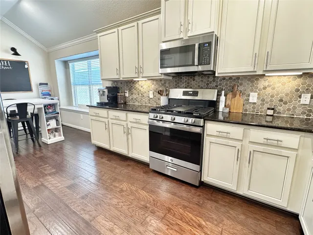 a kitchen with stainless steel appliances granite countertop a stove a sink and a microwave