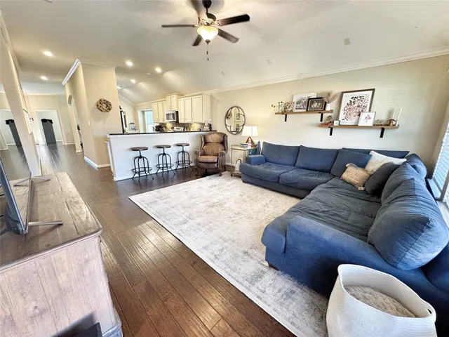 a living room with furniture kitchen view and a wooden floor