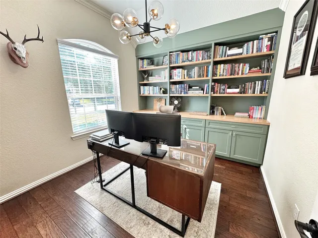 a work room with furniture bookshelf and a window