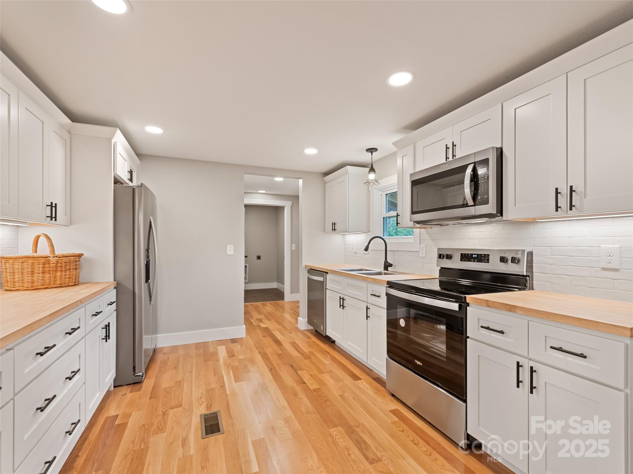 120 Simonds Ridge Canton, NC 28716 - Photo 6 of 36 a open kitchen with stainless steel appliances granite countertop a refrigerator a stove top oven a sink dishwasher and white cabinets with wooden floor