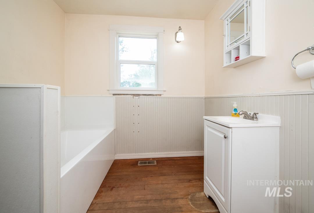 595 Cemetery Road Cambridge, ID 83610 - Photo 18 of 47 Bathroom with wood-finish flooring, beadboard wainscoting, and a white vanity with an integrated sink