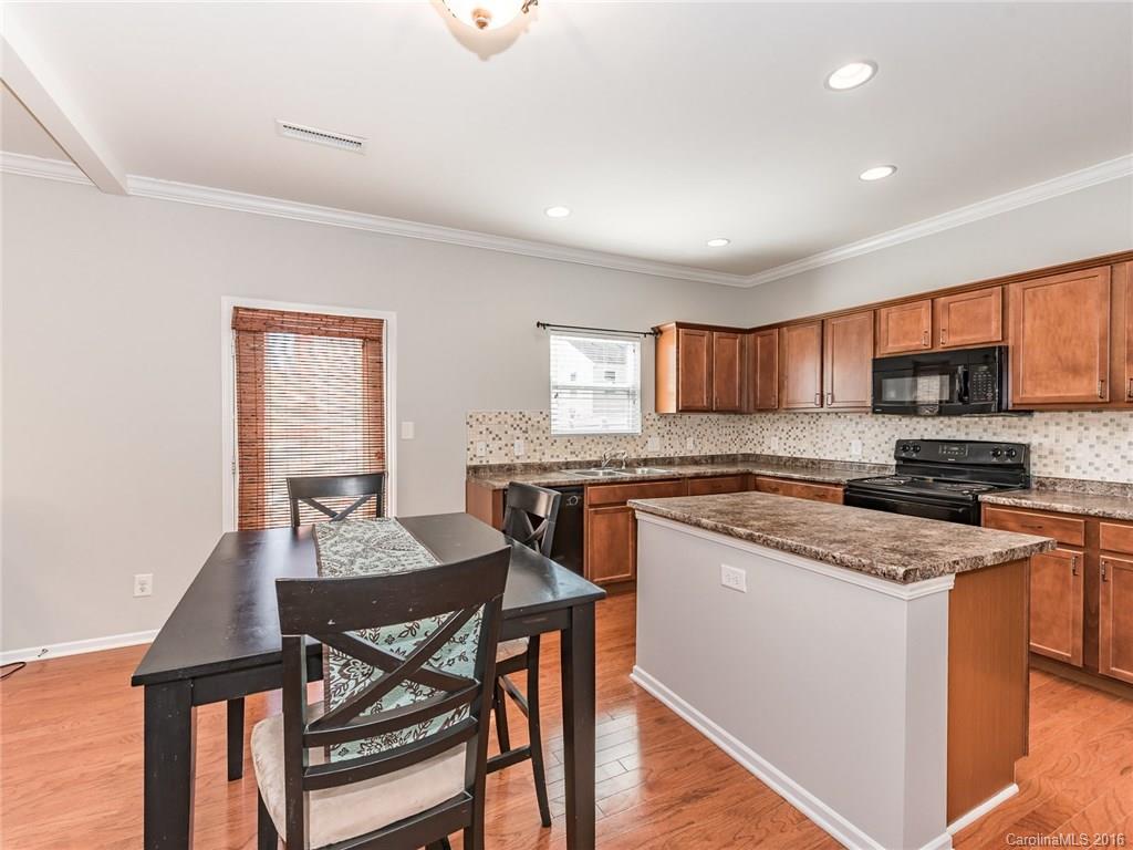 2226 Durand Road Fort Mill, SC 29715 - Photo 12 of 24 a kitchen with stainless steel appliances granite countertop a stove top oven a sink a refrigerator with a dining table and chairs with wooden floor