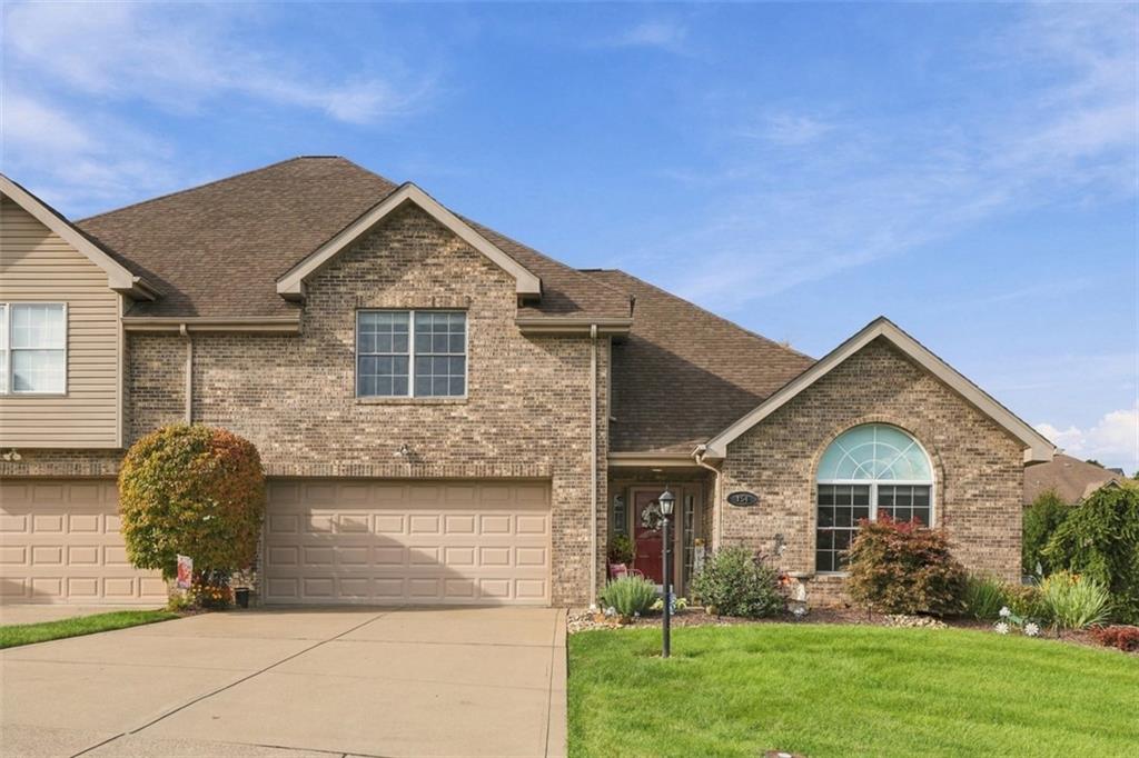 Level-entry end-unit with a wide driveway and professionally landscaped grounds creating a welcoming first impression.