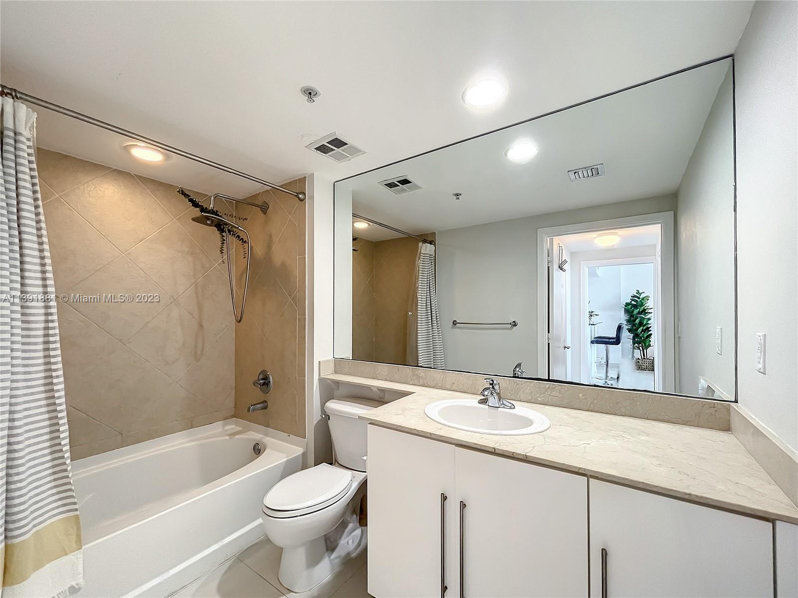 335 South Biscayne Boulevard, Unit 3103 Miami, FL 33131 - Photo 14 of 35 a bathroom with a granite countertop sink toilet mirror and bathtub