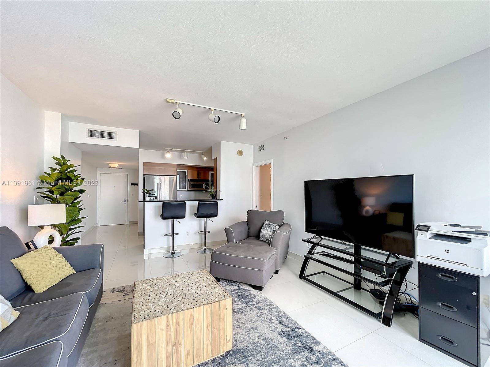 335 South Biscayne Boulevard, Unit 3103 Miami, FL 33131 - Photo 5 of 35 a living room with furniture and a flat screen tv