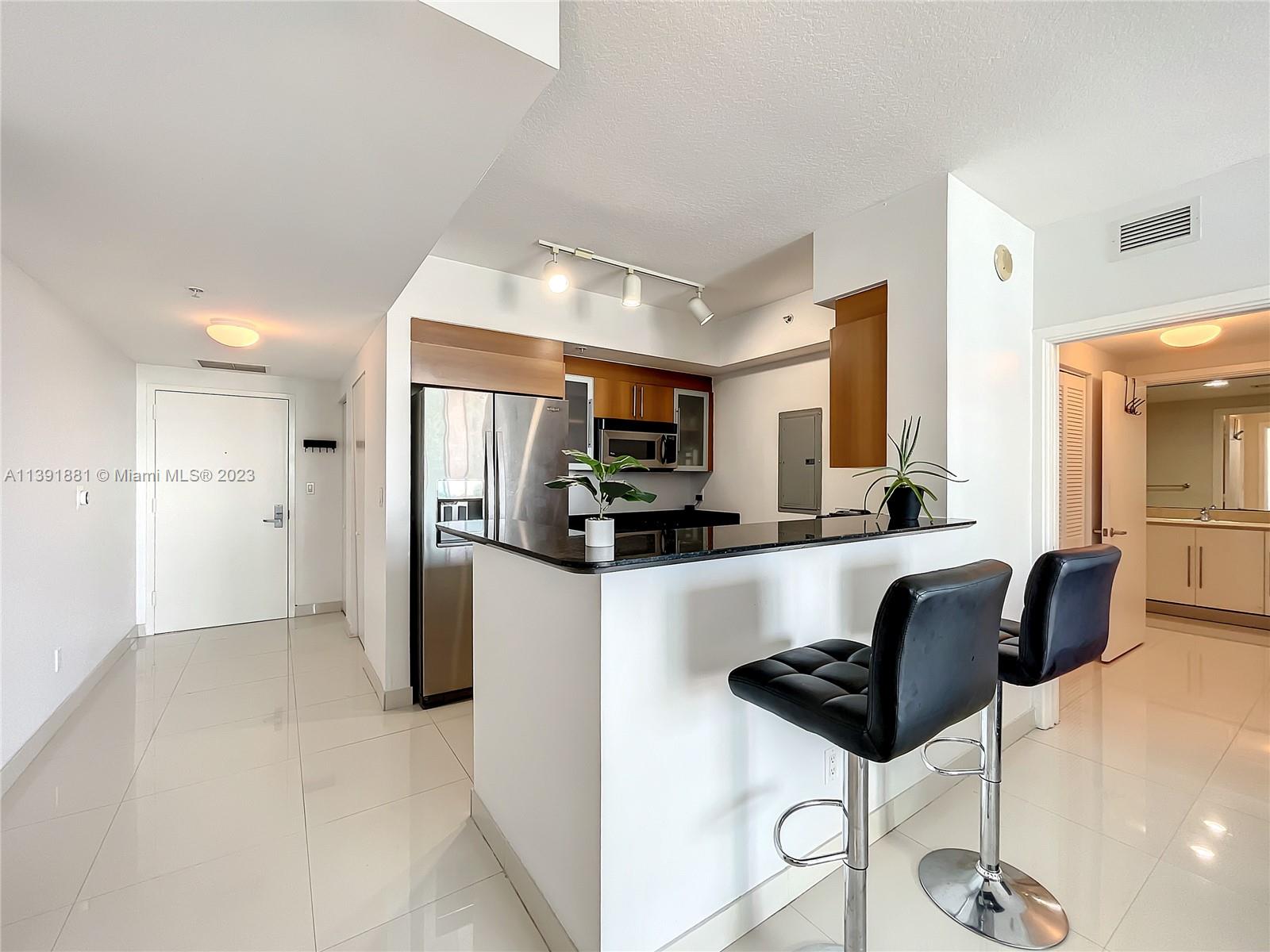 335 South Biscayne Boulevard, Unit 3103 Miami, FL 33131 - Photo 7 of 35 a kitchen with stainless steel appliances kitchen island granite countertop a refrigerator and a sink