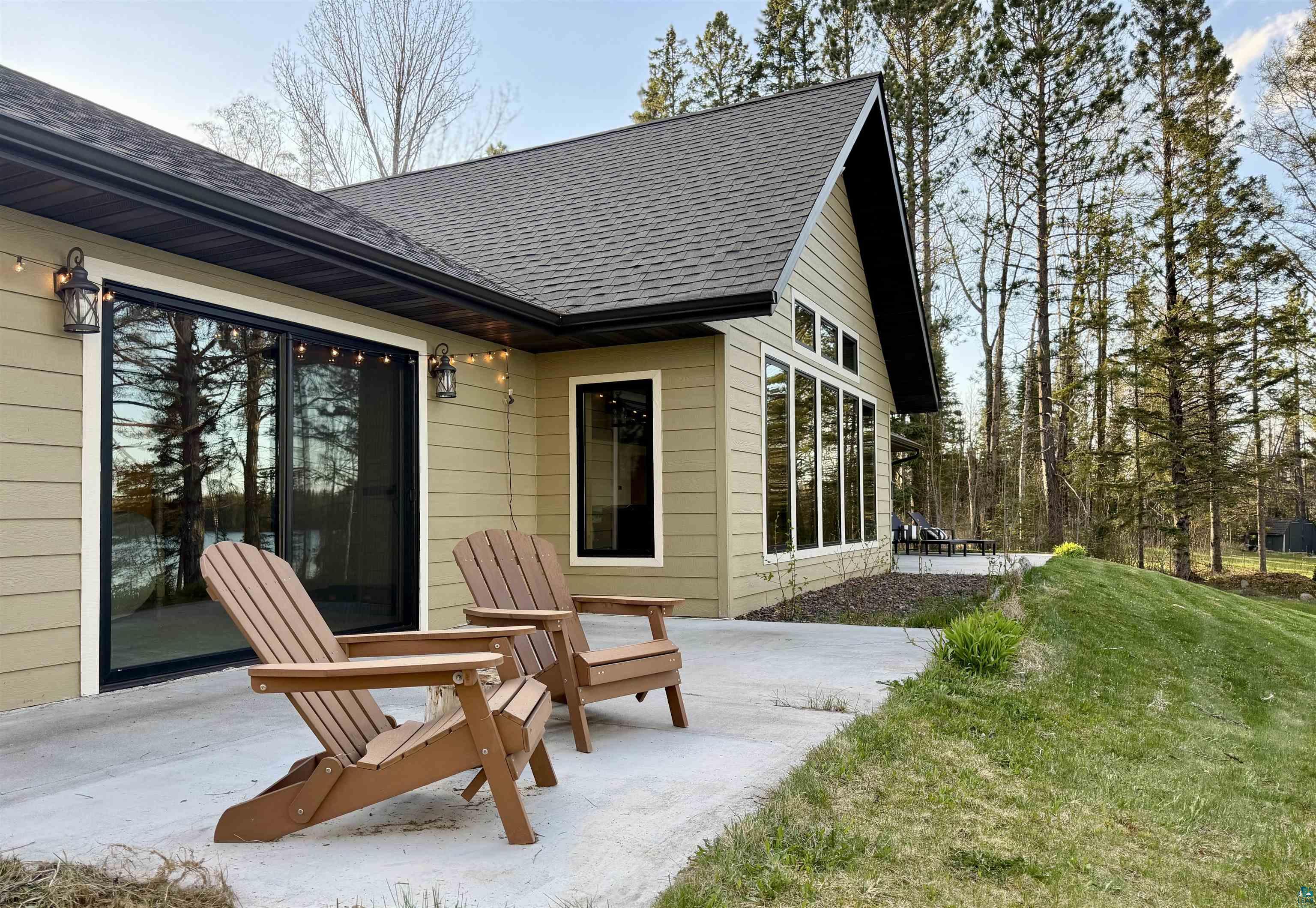 5274 Marble Lake Road Two Harbors, MN 55616 - Photo 36 of 79 Rear concrete patio featuring a sliding glass door, multiple large windows, and an exterior with horizontal siding