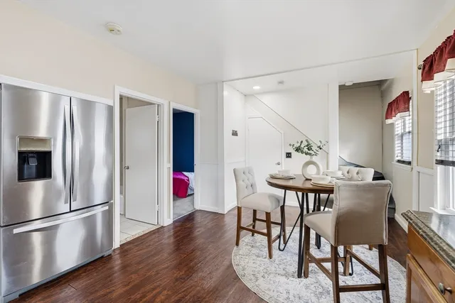 a kitchen with stainless steel appliances granite countertop a refrigerator a stove a dining table and chairs with wooden floor