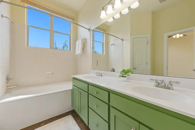 a bathroom with a double vanity sink mirror and bathtub