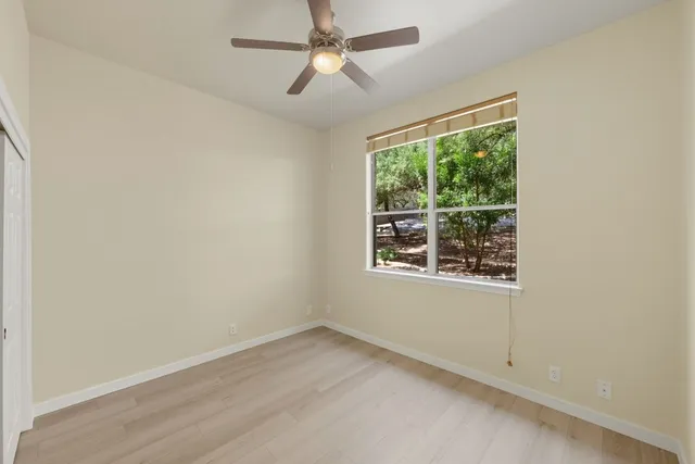 an empty room with a window and ceiling fan