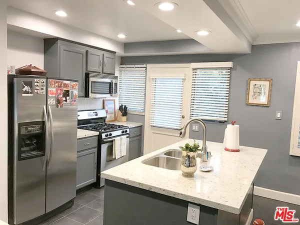 a kitchen with stainless steel appliances granite countertop a refrigerator a stove a sink a washer and island
