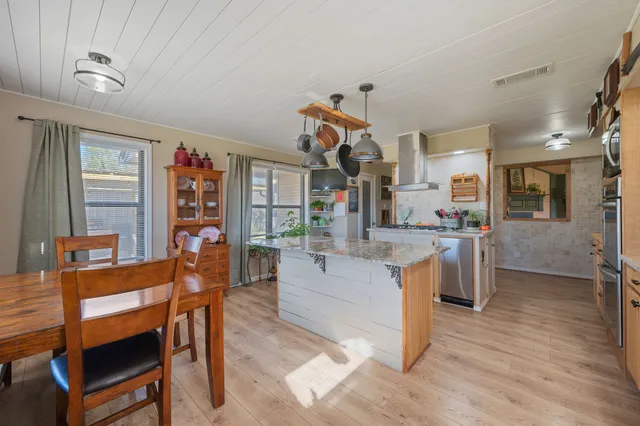 a kitchen with stainless steel appliances granite countertop a stove a sink dishwasher and a refrigerator with wooden floor