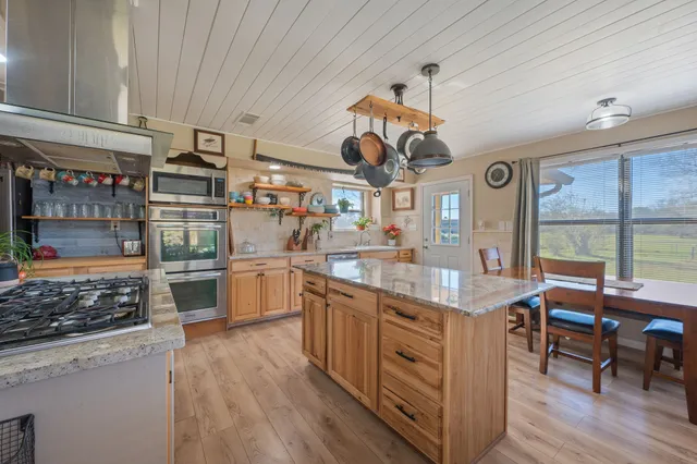 a kitchen with a stove a window and chairs