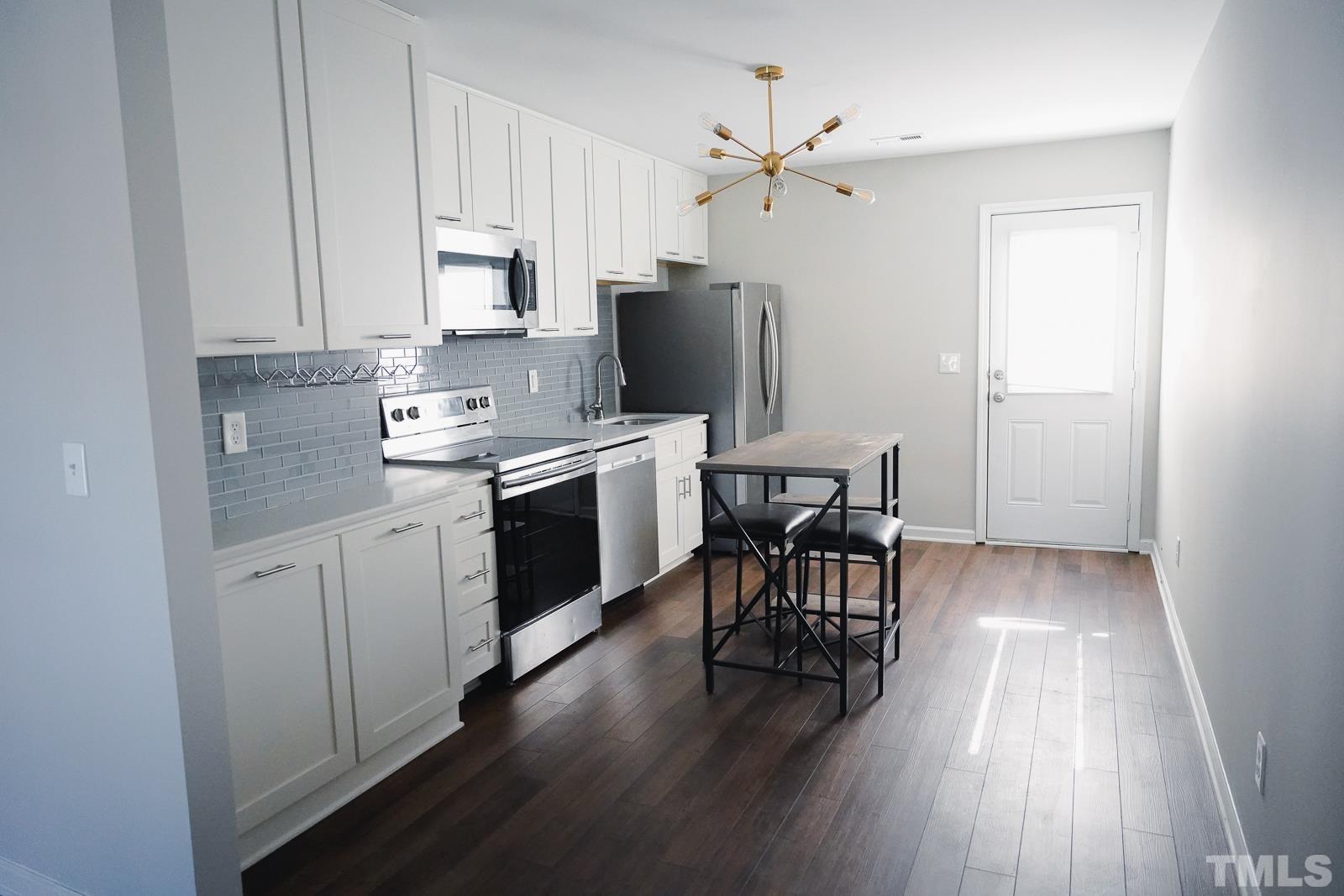 1320 South State Street, Unit A Raleigh, NC 27610 - Photo 6 of 20 a kitchen with a table chairs refrigerator and microwave
