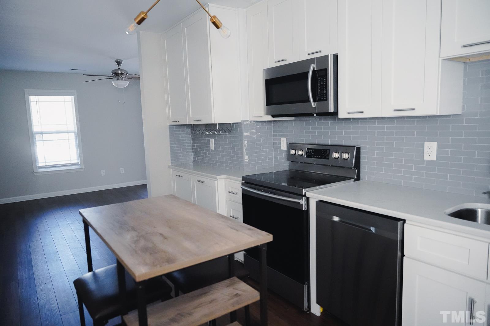 1320 South State Street, Unit A Raleigh, NC 27610 - Photo 8 of 20 a kitchen with a table chairs microwave and cabinets