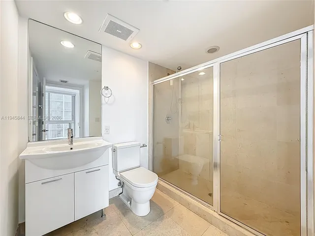 a bathroom with a shower sink vanity mirror and toilet
