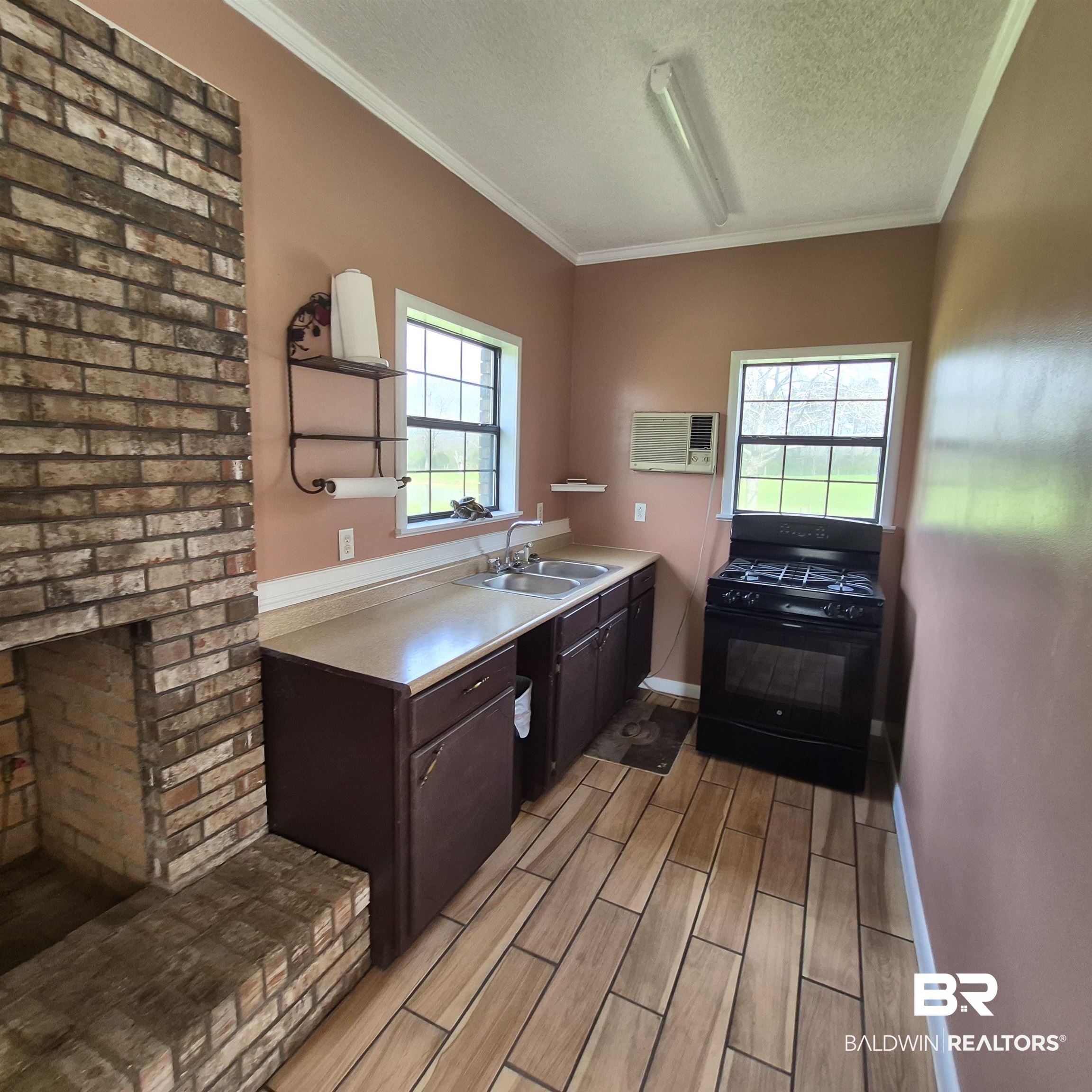 26635 Highway 41 Range, AL 36473 - Photo 48 of 74 Kitchen with dark wood finish cabinetry, wood tiled floors, black range with gas cooktop, light countertops, and a textured ceiling