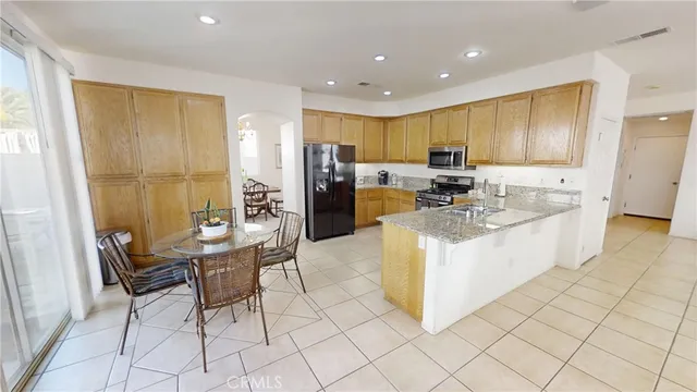 a view of kitchen with stainless steel appliances kitchen island granite countertop dining table chair and a refrigerator