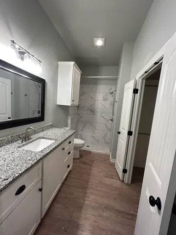 a bathroom with a granite countertop sink toilet and shower
