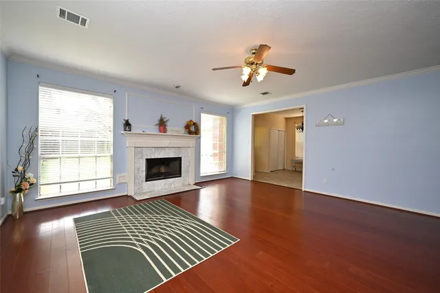 an empty room with windows a fireplace and wooden floor
