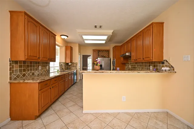 a kitchen with stainless steel appliances granite countertop a refrigerator a sink and a stove