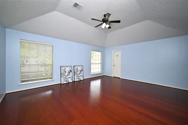 a view of an empty room with a window and wooden floor