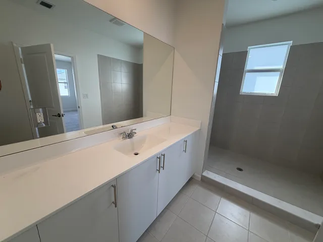 a spacious bathroom with a shower sink and mirror