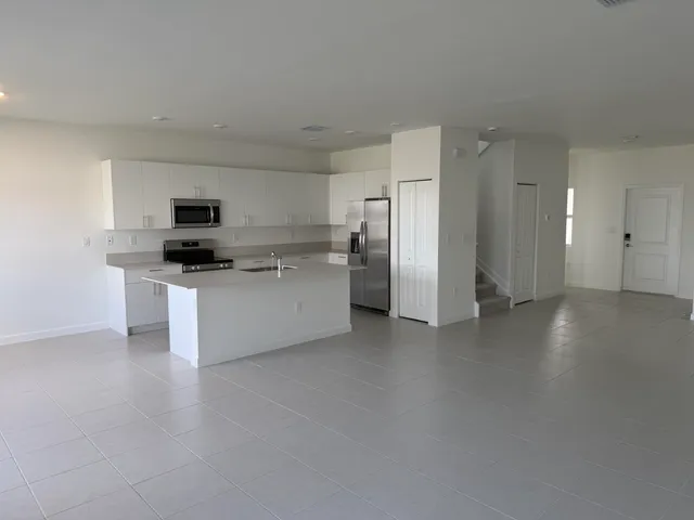 a kitchen with stainless steel appliances a refrigerator a stove a sink and white cabinets