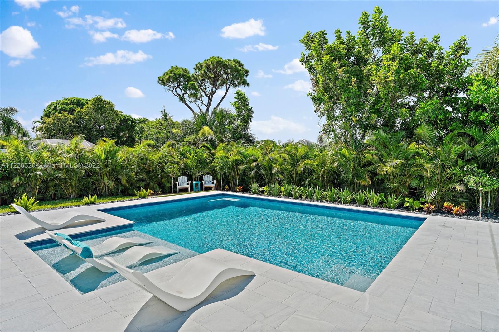 19 Shay Place Tequesta, FL 33469 - Photo 41 of 46 a view of a swimming pool with lawn chairs and plants
