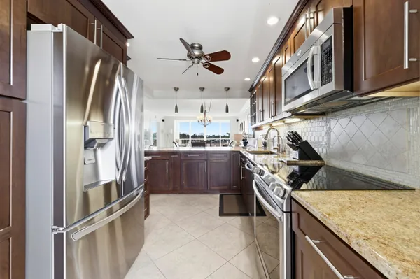 a kitchen with stainless steel appliances granite countertop a refrigerator a stove and a sink