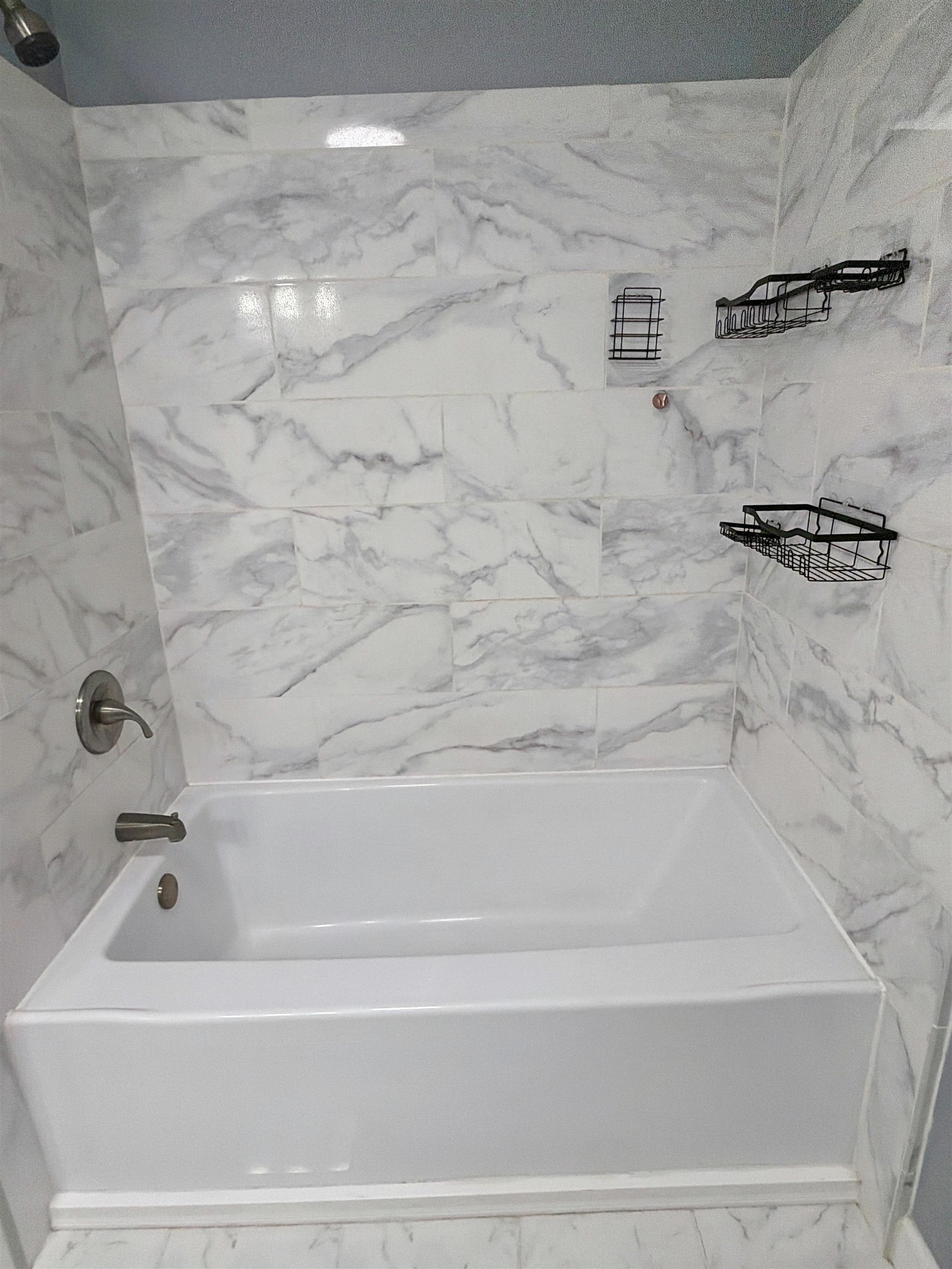 8022 45th Highway Ramer, TN 38367 - Photo 10 of 21 White bathtub with brushed nickel fixtures, white and gray marble-patterned tile, and integrated shower caddies