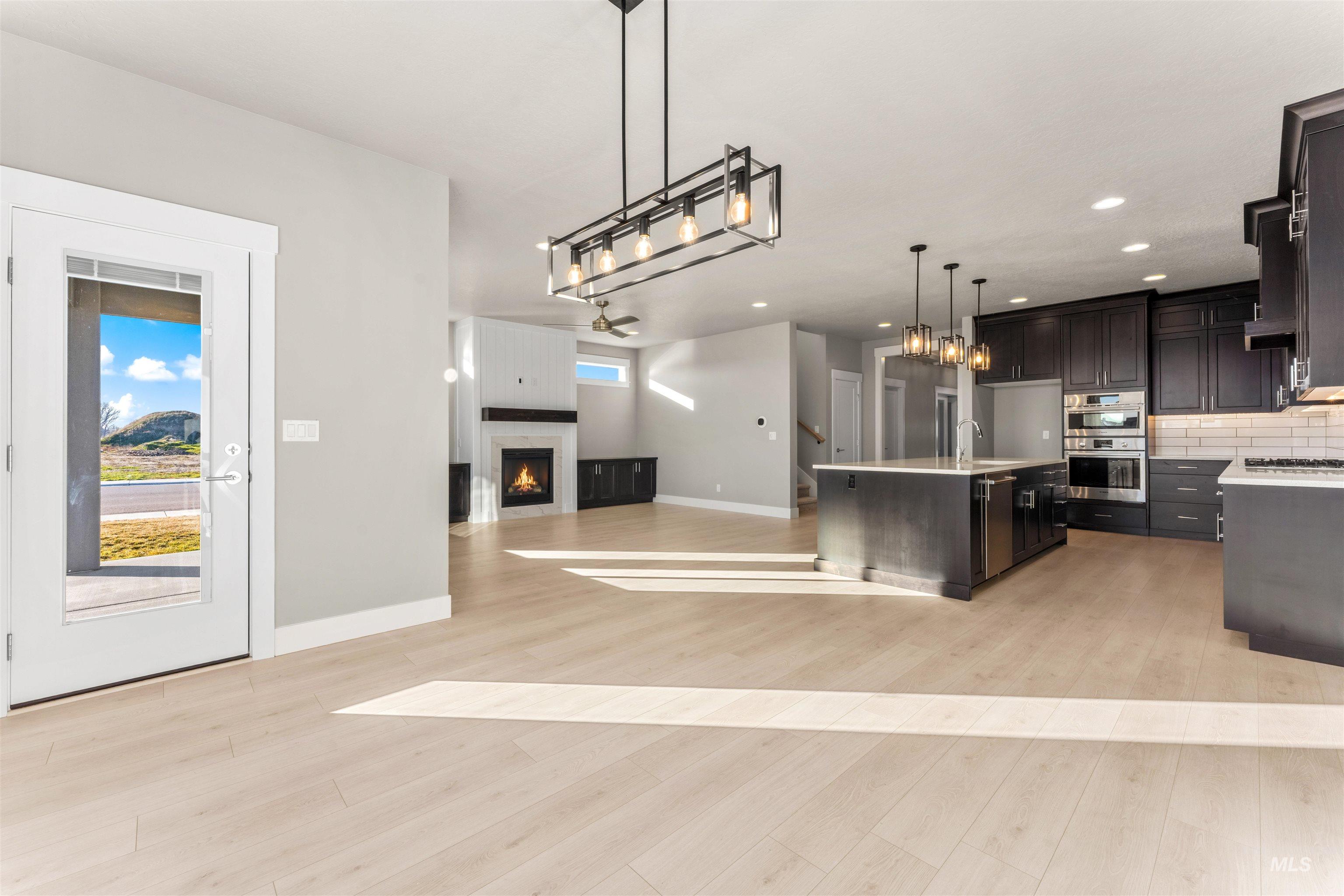 8081 Tandy Cove Street Middleton, ID 83644 - Photo 41 of 41 Kitchen with open floor plan, a fireplace, pendant lighting, tasteful backsplash, and stainless steel appliances