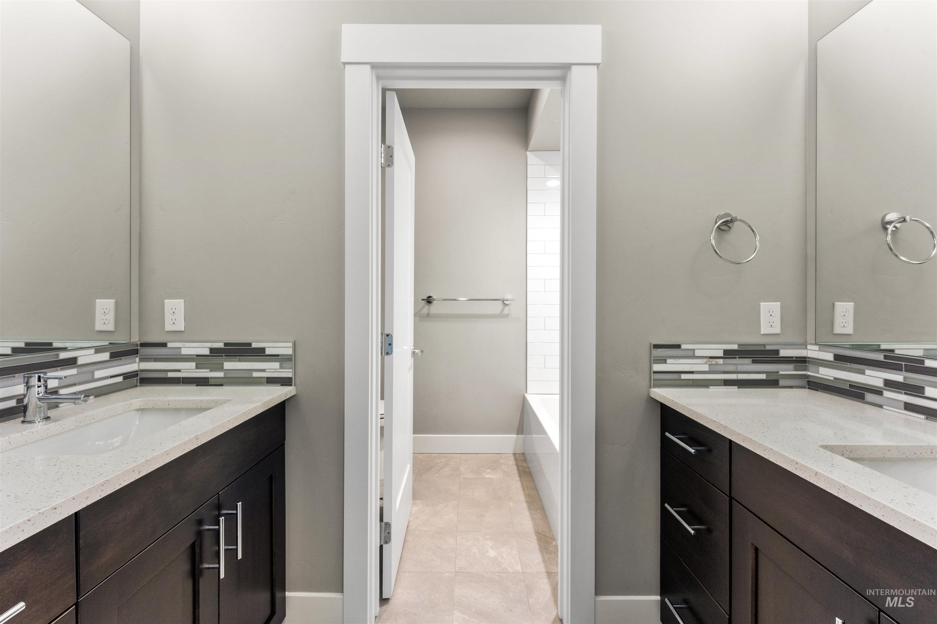 8081 Tandy Cove Street Middleton, ID 83644 - Photo 29 of 41 Bathroom featuring backsplash, two vanities, a bath, and light tile patterned floors