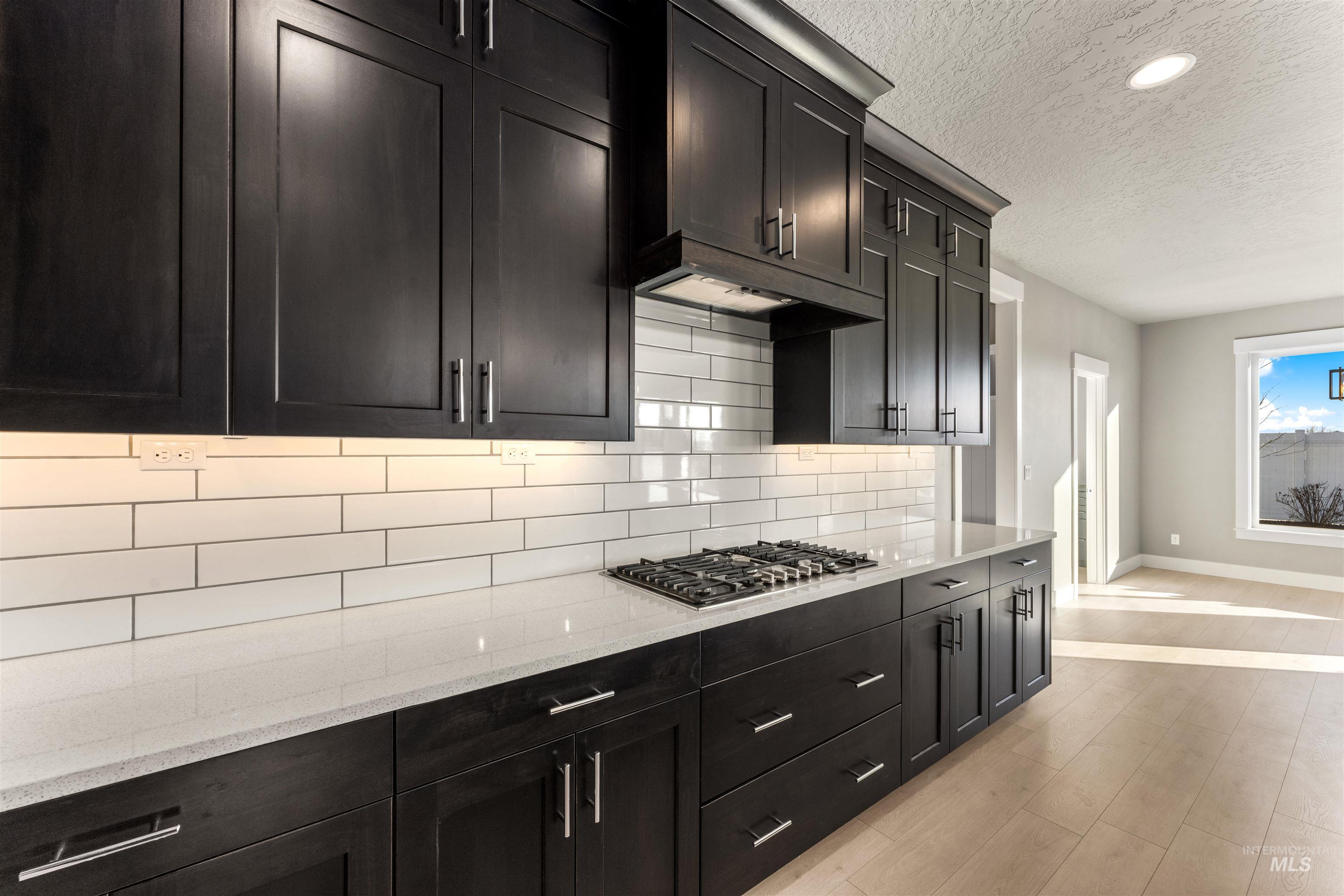 8081 Tandy Cove Street Middleton, ID 83644 - Photo 7 of 41 Kitchen featuring light stone counters, a textured ceiling, decorative backsplash, stainless steel gas stovetop, and recessed lighting