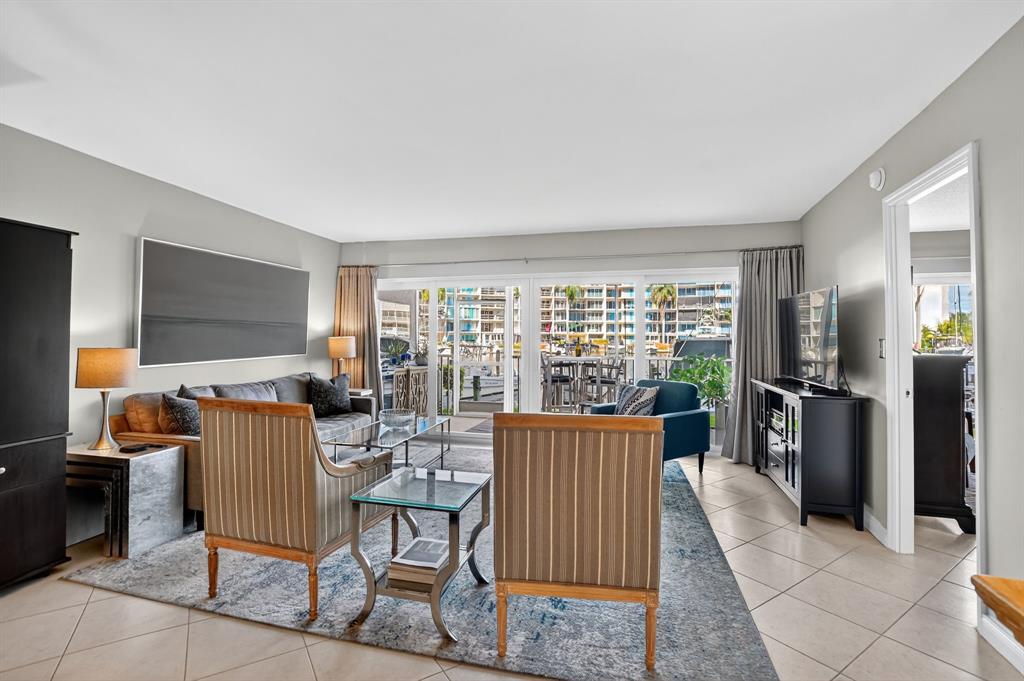 1537 East Hillsboro Boulevard, Unit 138 Deerfield Beach, FL 33441 - Photo 21 of 43 a living room with furniture a flat screen tv and a floor to ceiling window