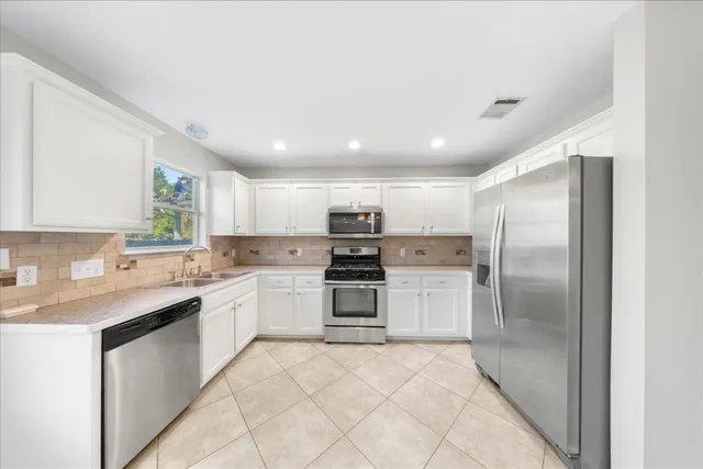 a large kitchen with stainless steel appliances granite countertop a stove a sink and a refrigerator