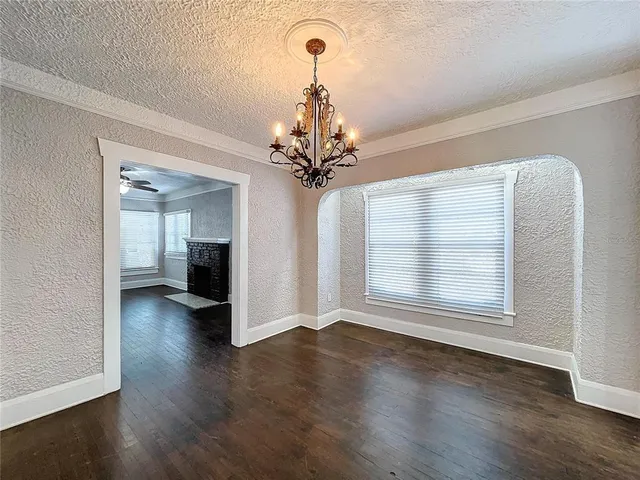 a view of a room with wooden floor chandelier and windows