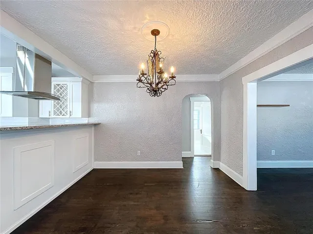 a view of a room with wooden floor chandelier and windows
