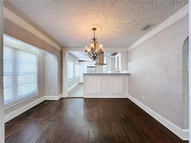 a view of a room with wooden floor chandelier and windows