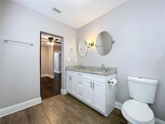 a bathroom with a granite countertop toilet sink and mirror