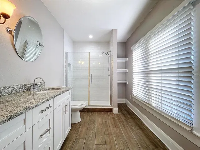 a bathroom with a granite countertop sink a mirror a vanity and a window