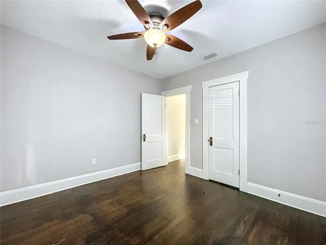 an empty room with wooden floor and ceiling fan