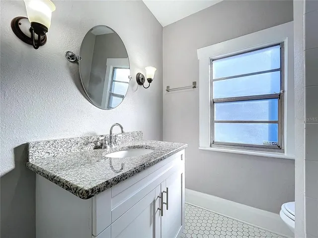 a bathroom with a granite countertop sink and a mirror