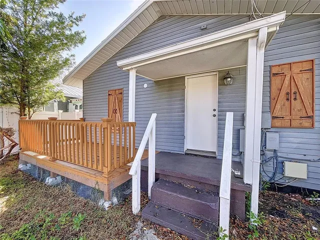 a view of a wooden house with a bench and a yard