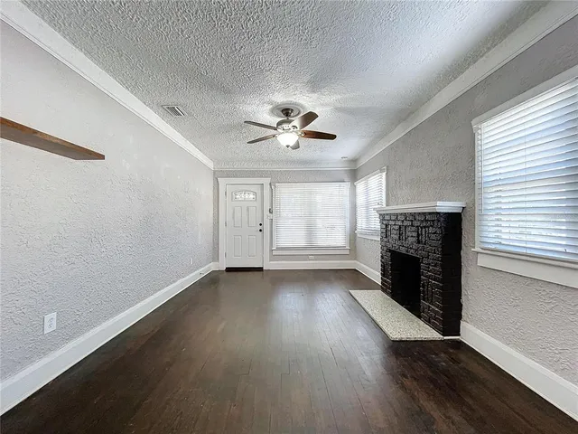 an empty room with wooden floor fireplace and windows