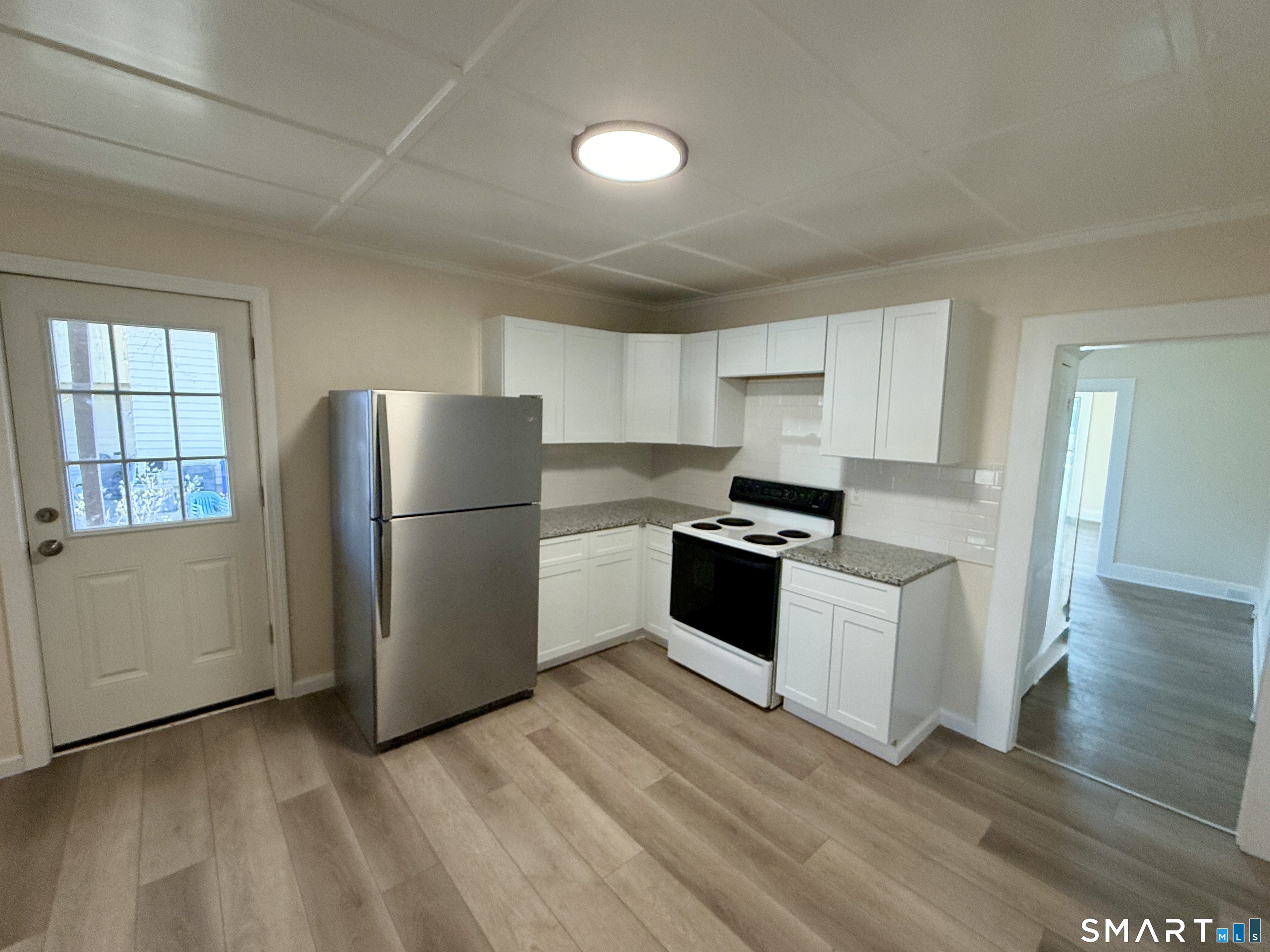 690 Main Street, Unit 1 Torrington, CT 06790 - Photo 2 of 12 a kitchen with granite countertop a refrigerator stove top oven and cabinets
