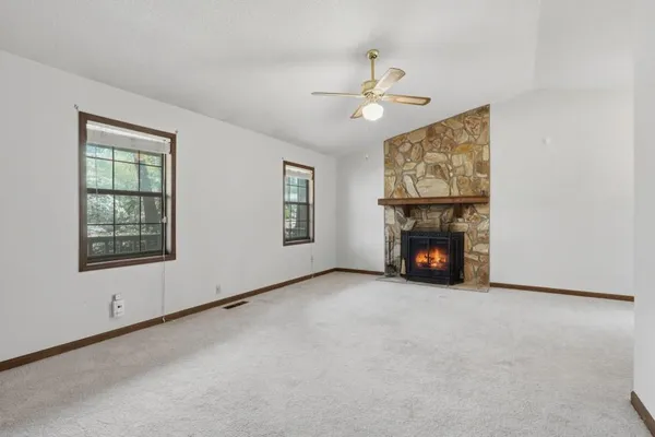 an empty room with windows fireplace and fans