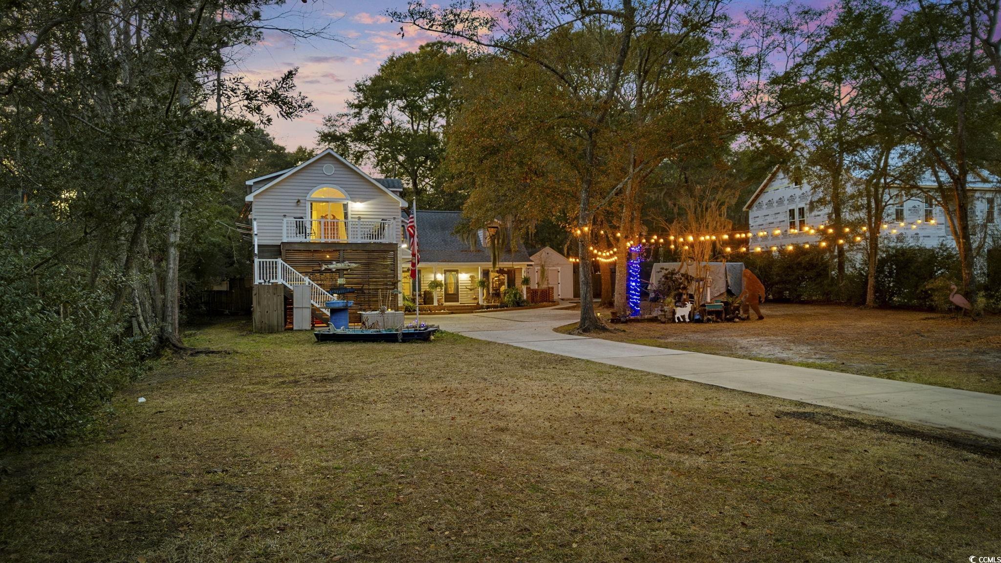 153 Watson Way Pawleys Island, SC 29585 - Photo 2 of 40 Yard at dusk featuring a lawn, driveway, and stairway