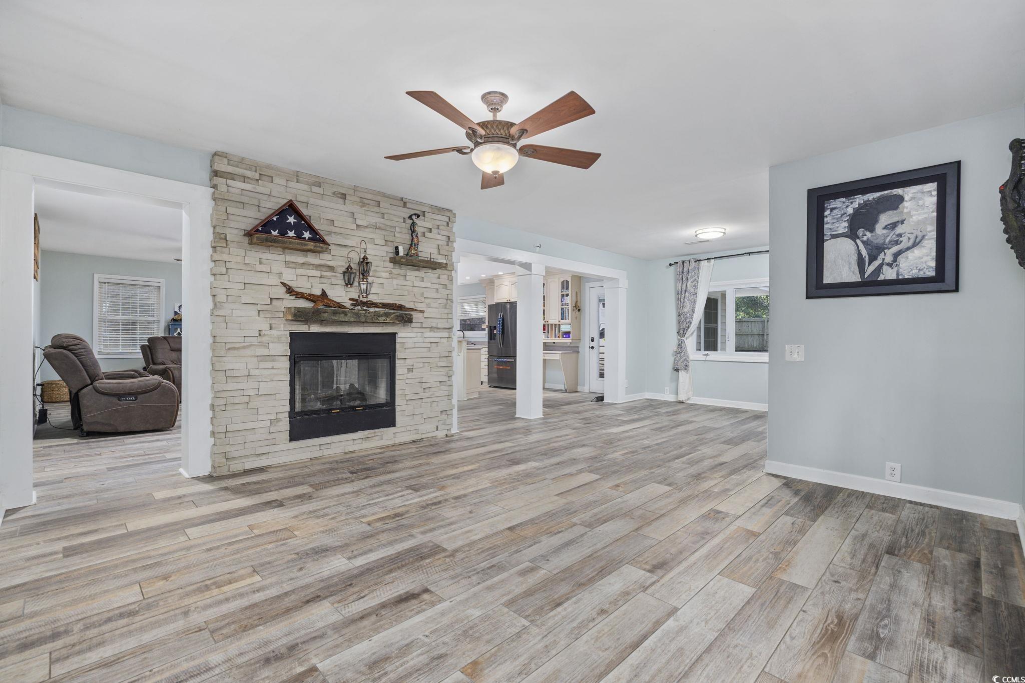153 Watson Way Pawleys Island, SC 29585 - Photo 6 of 40 Unfurnished living room featuring a stone fireplace, light wood-type flooring, and a ceiling fan